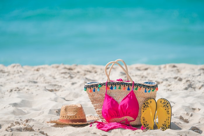 Beach accessories: straw bag, bikini, flip-flops, and hat