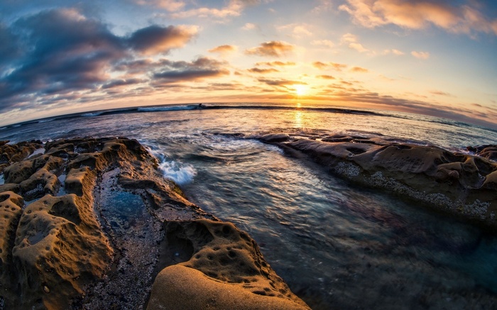 Sunset over the ocean with rocky shore