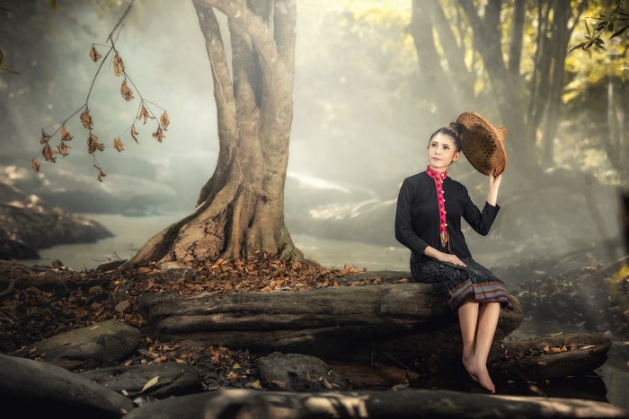 Woman in traditional clothing sitting by a tree
