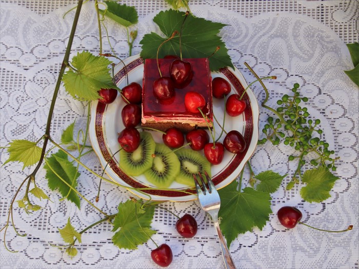 Slice of cherry cake with kiwi and cherries on a plate