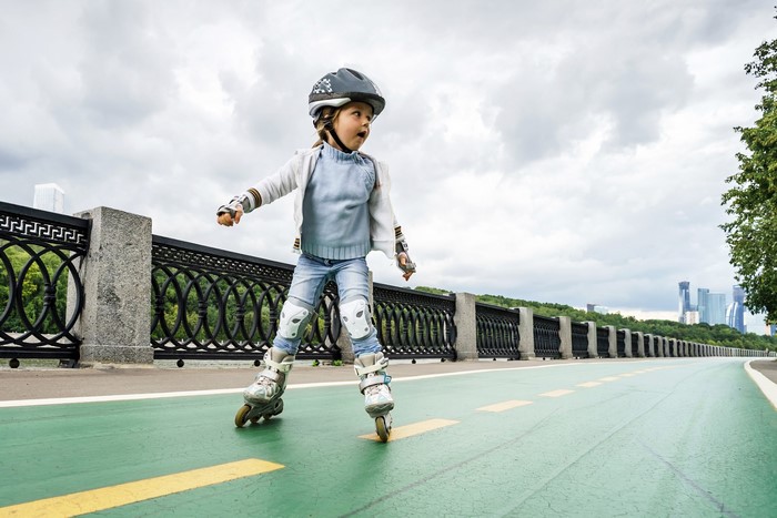 Girl in helmet and roller skates on a path