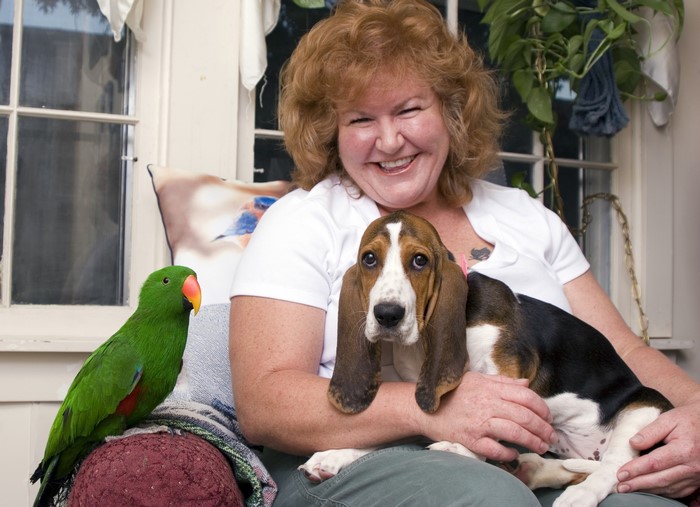 Woman with Basset Hound puppy and green parrot