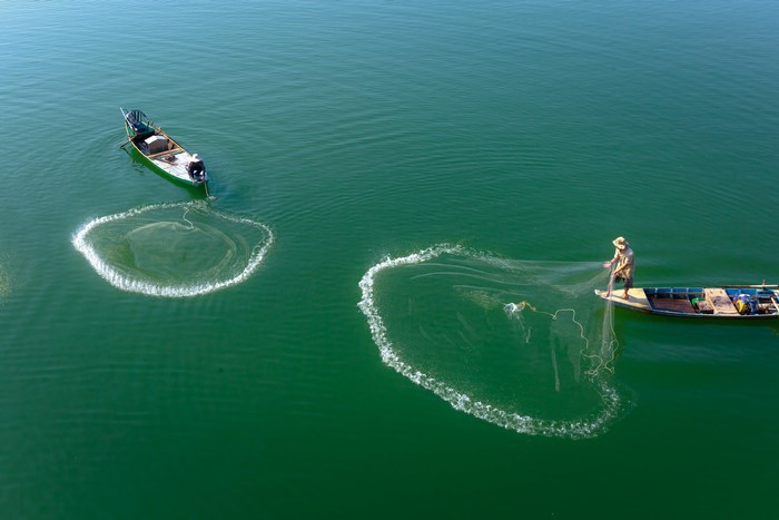 Two fishermen casting nets from boats in Vietnam