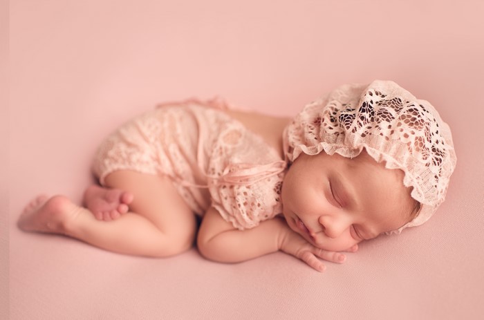 Newborn baby sleeping on pink background