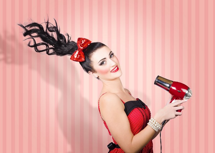 Brunette girl with hair dryer and red bowknot