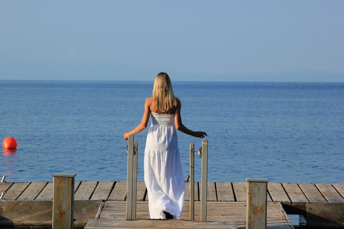 Blonde woman in white dress on a pier