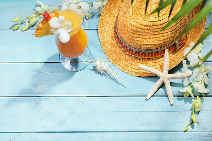 Tropical drink with orchid and straw hat on blue wood