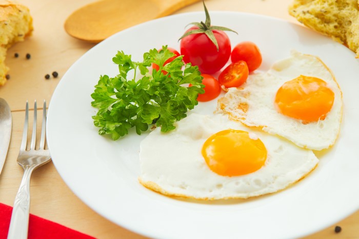 Fried eggs with tomatoes and parsley on a plate