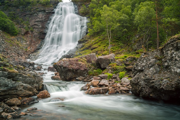 Waterfall cascading over rocks with surrounding forest