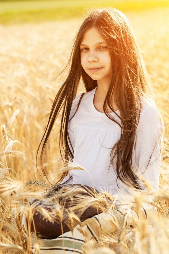 Girl in a wheat field holding bread