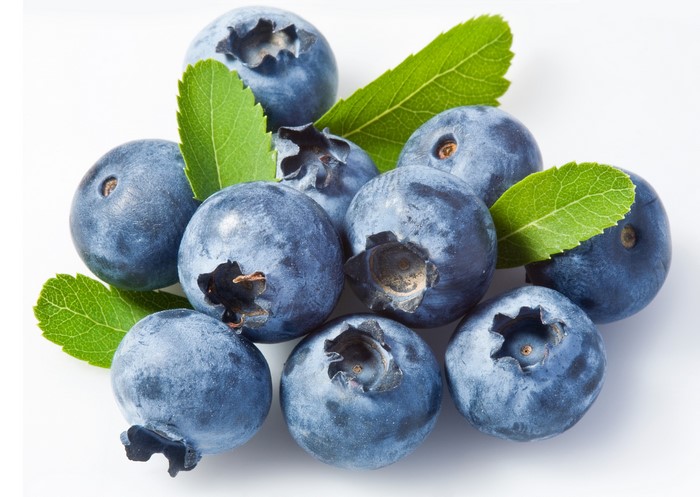Blueberries with green leaves on white background