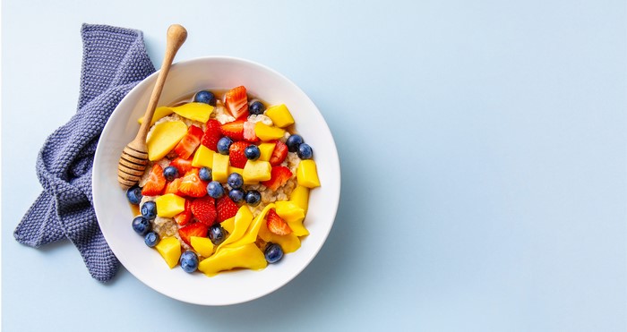 Bowl of muesli with strawberries, blueberries, mango, and honey