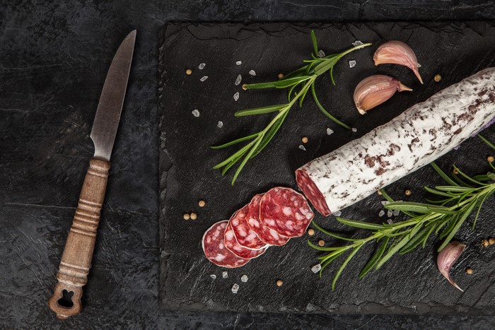 Sliced salami with rosemary and garlic on a slate board