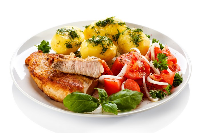 Pork chop with potatoes and tomato salad on a plate