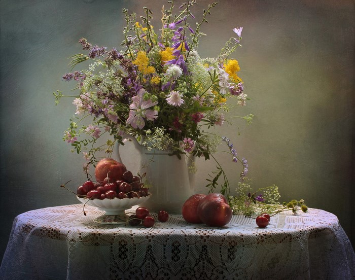 Still-life with bouquet, peaches, and cherries on a tablecloth