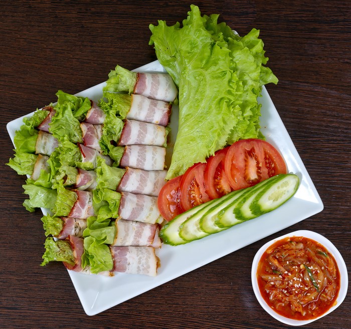 Bacon-wrapped lettuce rolls with tomatoes, cucumbers, and kimchi