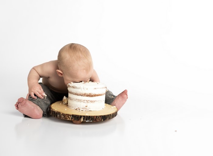 Baby boy eating cake on white background