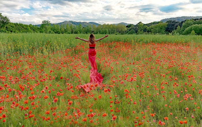Woman in red dress in a field of poppies