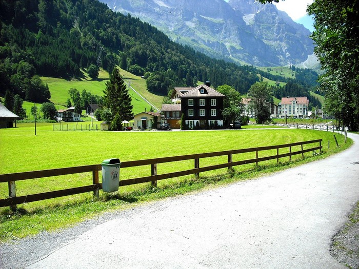 Houses and fence in a green valley with Alps mountains