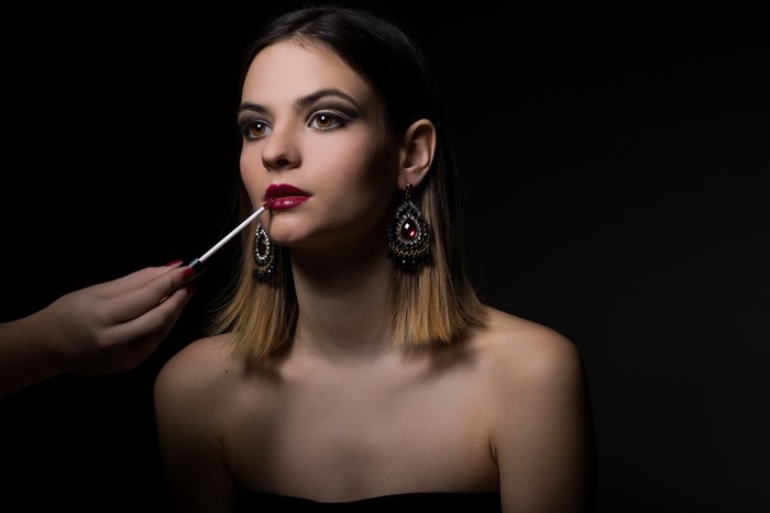 Woman applying red lipstick with makeup brush
