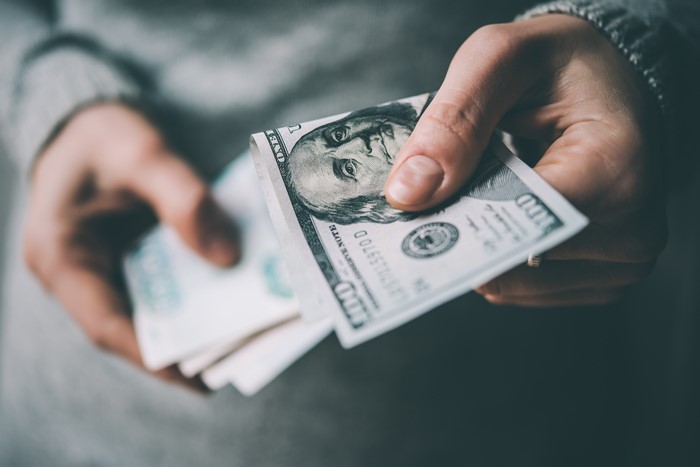 Hands holding 100 dollar bills and other banknotes