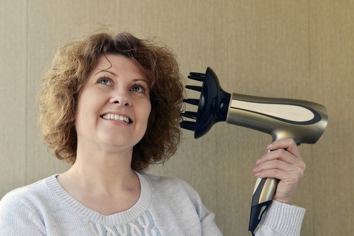 Woman drying curly hair with a diffuser hair dryer