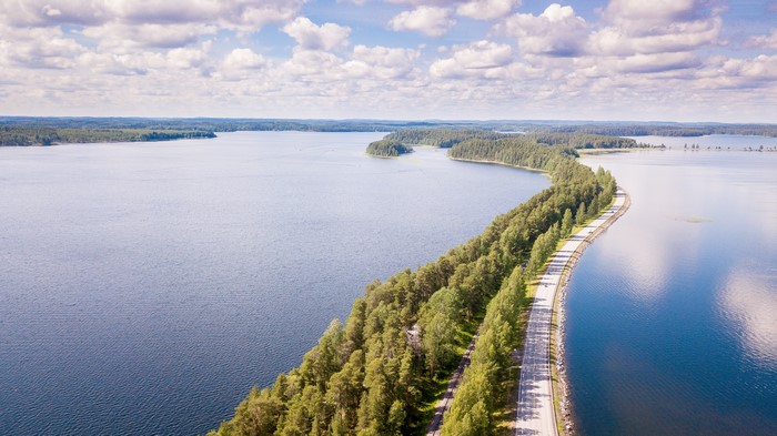 Road through forests along a lake in Punkaharju, Finland