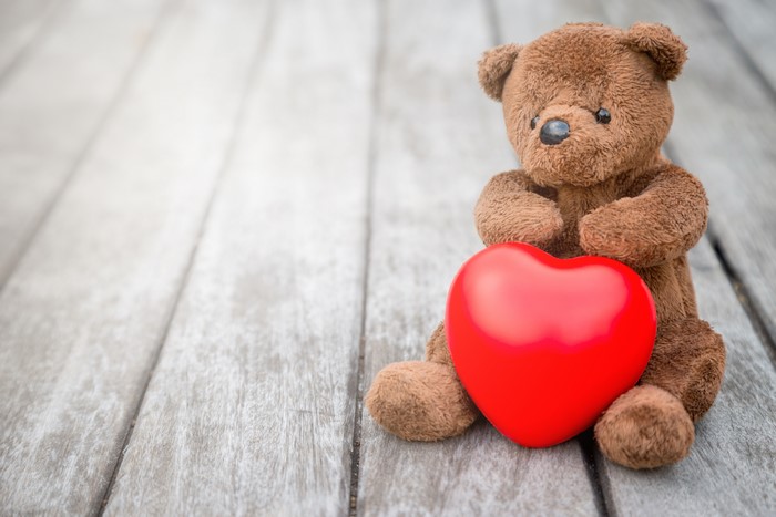 Teddy bear holding a red heart on wood planks