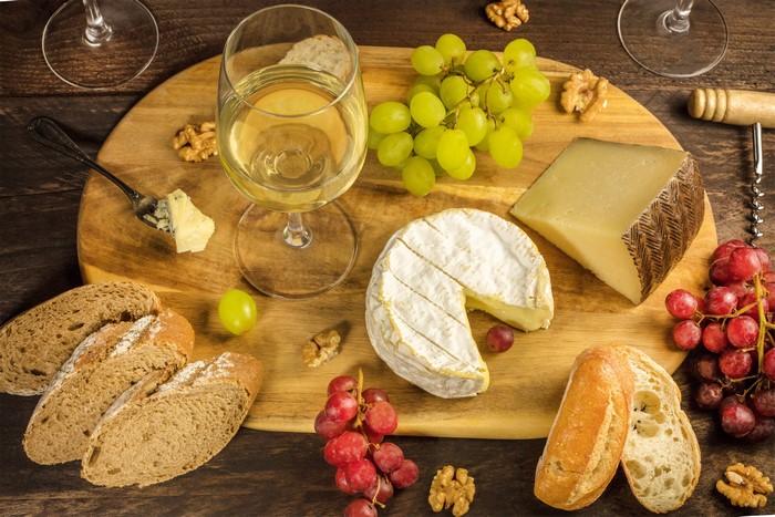 Wine, Cheese, Grapes, Bread, and Nuts on a Cutting Board