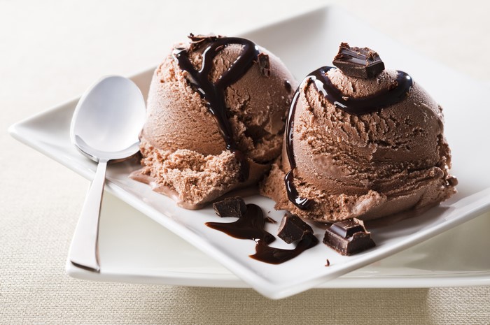 Chocolate ice cream scoops with chocolate syrup and spoon