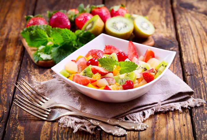 Fruit salad with strawberries and kiwi on a wooden table