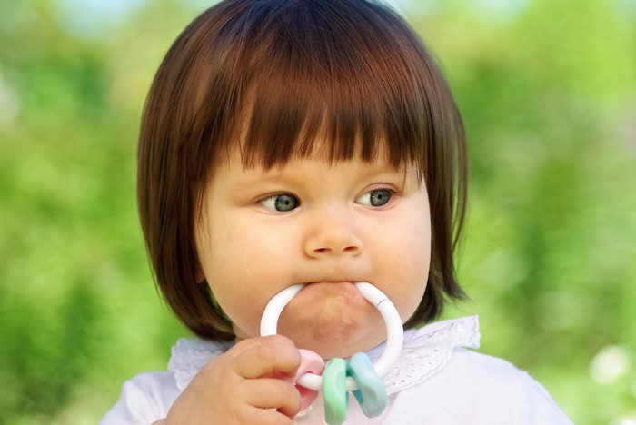 Baby girl chewing on a teething toy