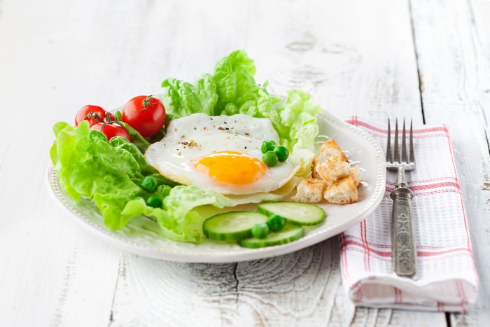 Fried egg breakfast with salad and croutons