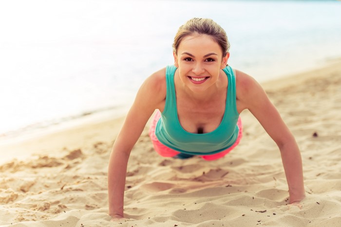 Woman doing push-ups on the beach