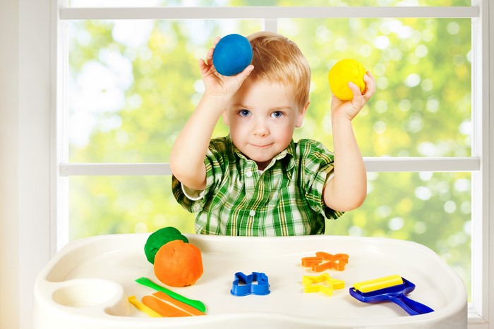 Boy playing with colorful playdough and toys
