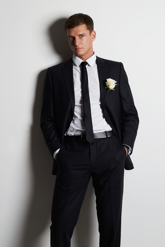 Man in a black suit with a white rose