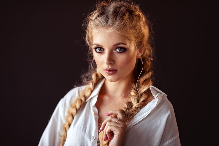 Lena Milovidova with braided hair against a black background