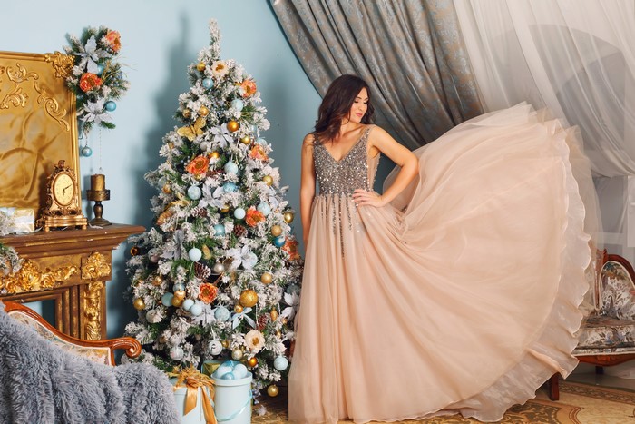 Woman in a sparkly dress by a Christmas tree