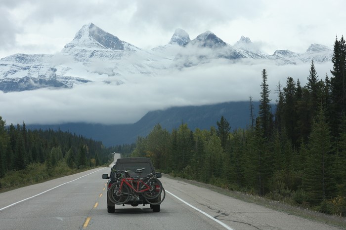 Car with bicycles on road in Rocky Mountains, Canada