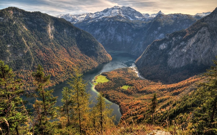 Mountain lake surrounded by autumn forest and snow-capped peaks