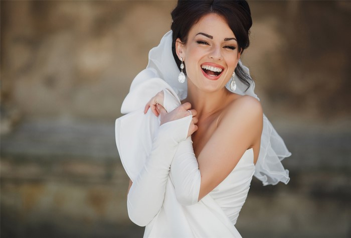 Bride laughing with veil and earrings