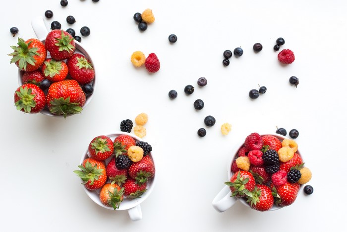 Three cups filled with strawberries, raspberries, blueberries, and blackberries