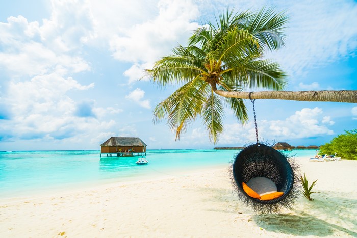 Tropical beach with overwater bungalow and hanging chair