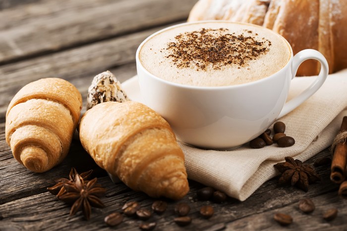 Cappuccino with croissants and star anise on wooden table