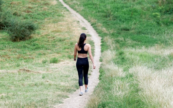 Brunette girl walking on a grassy trail