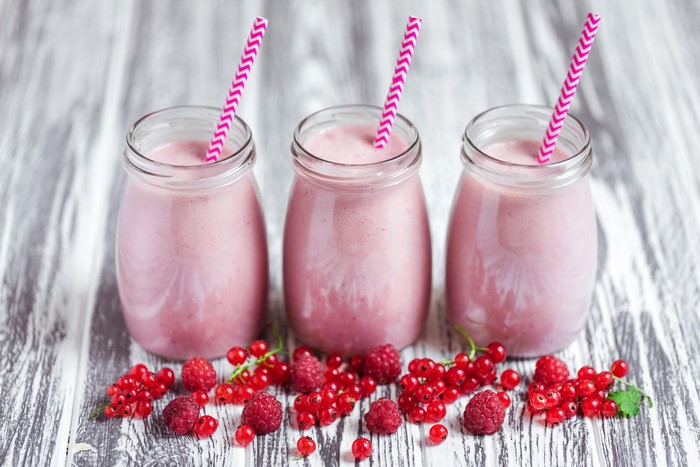 Three berry smoothies in jars with fresh berries