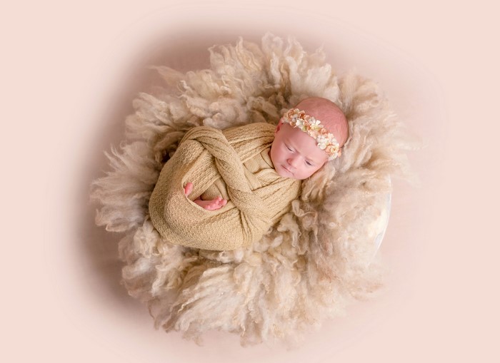 Newborn baby wrapped in a blanket with a floral headband