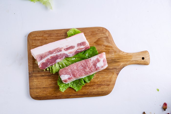 Pork belly on a cutting board with lettuce