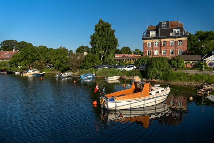 Motorboat in a Danish harbor with houses and trees
