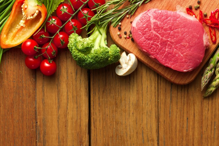 Raw steak and fresh vegetables on wooden planks